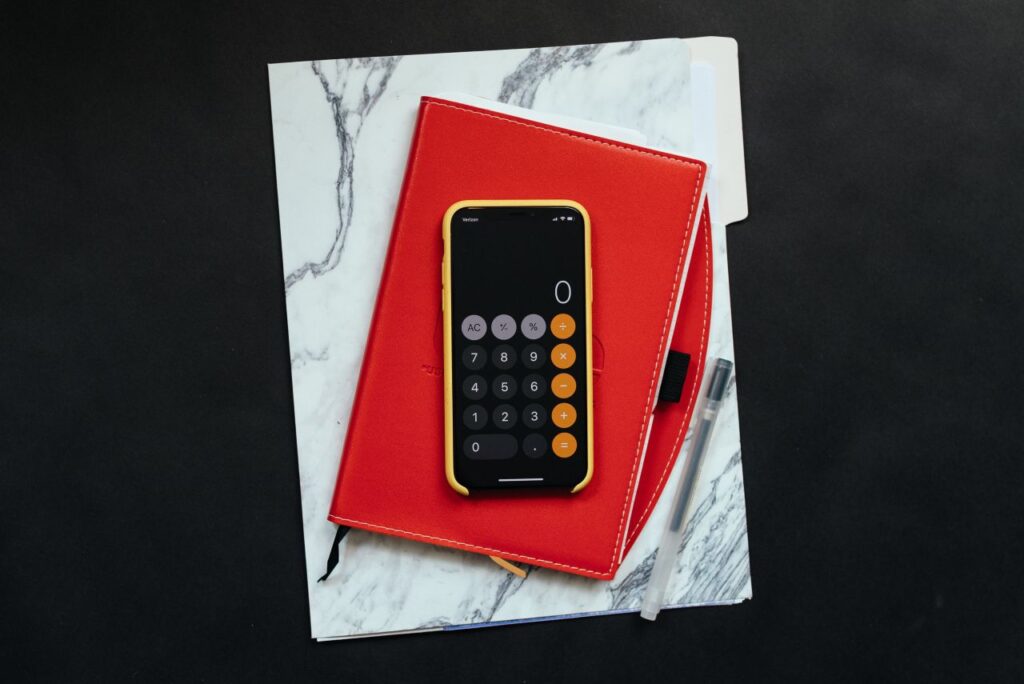 dossier red notebook and phone calculator on dark desk