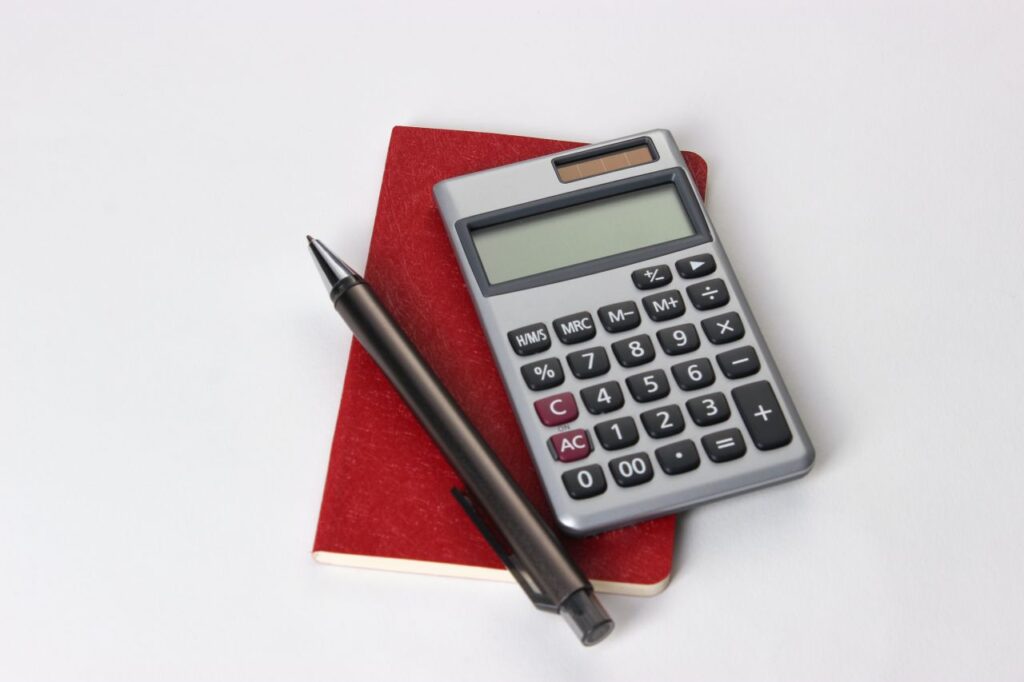 red notebook pencil and calculator on white table